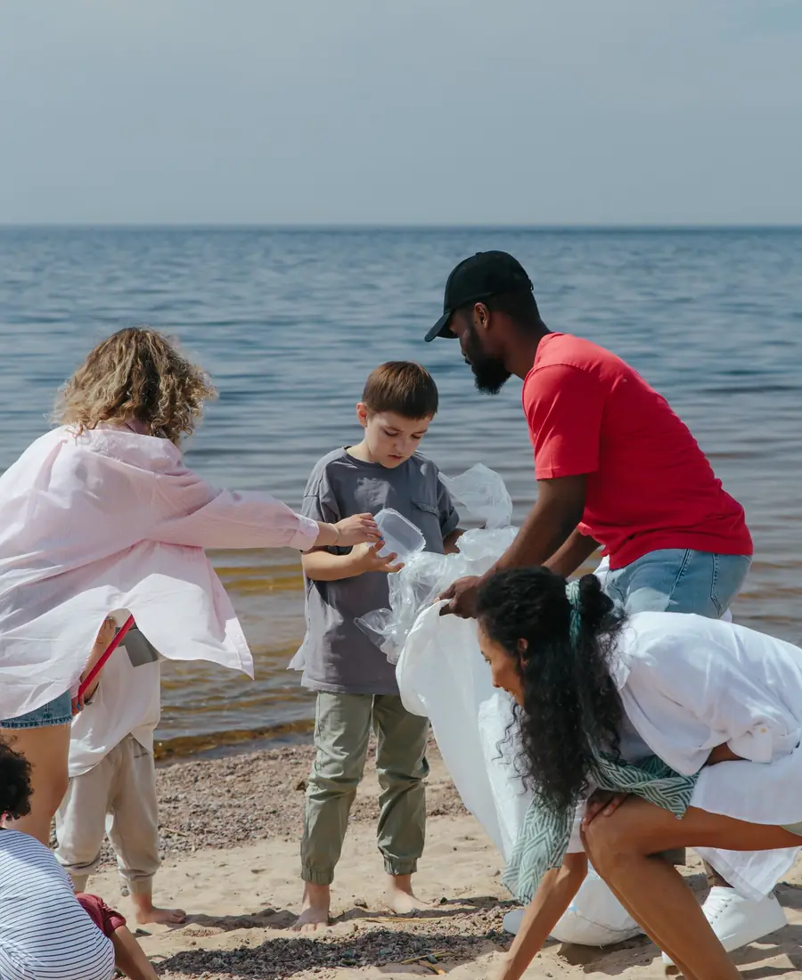 Volunteers of all ages collecting plastic trash on a sandy beach